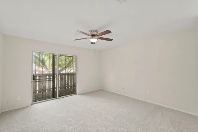 an empty room with a ceiling fan and window