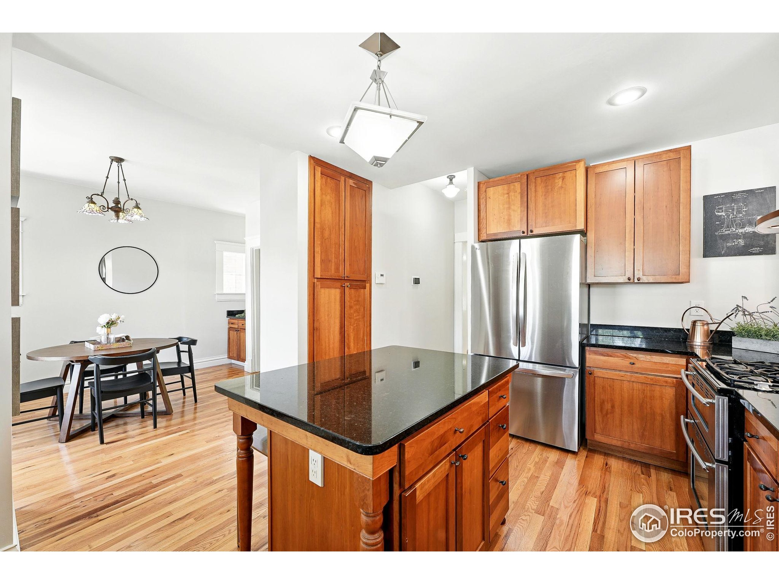 1582 Steele Street Denver, CO 80206 - Photo 17 of 48 a kitchen with stainless steel appliances granite countertop a refrigerator a sink dishwasher a dining table and chairs with wooden floor