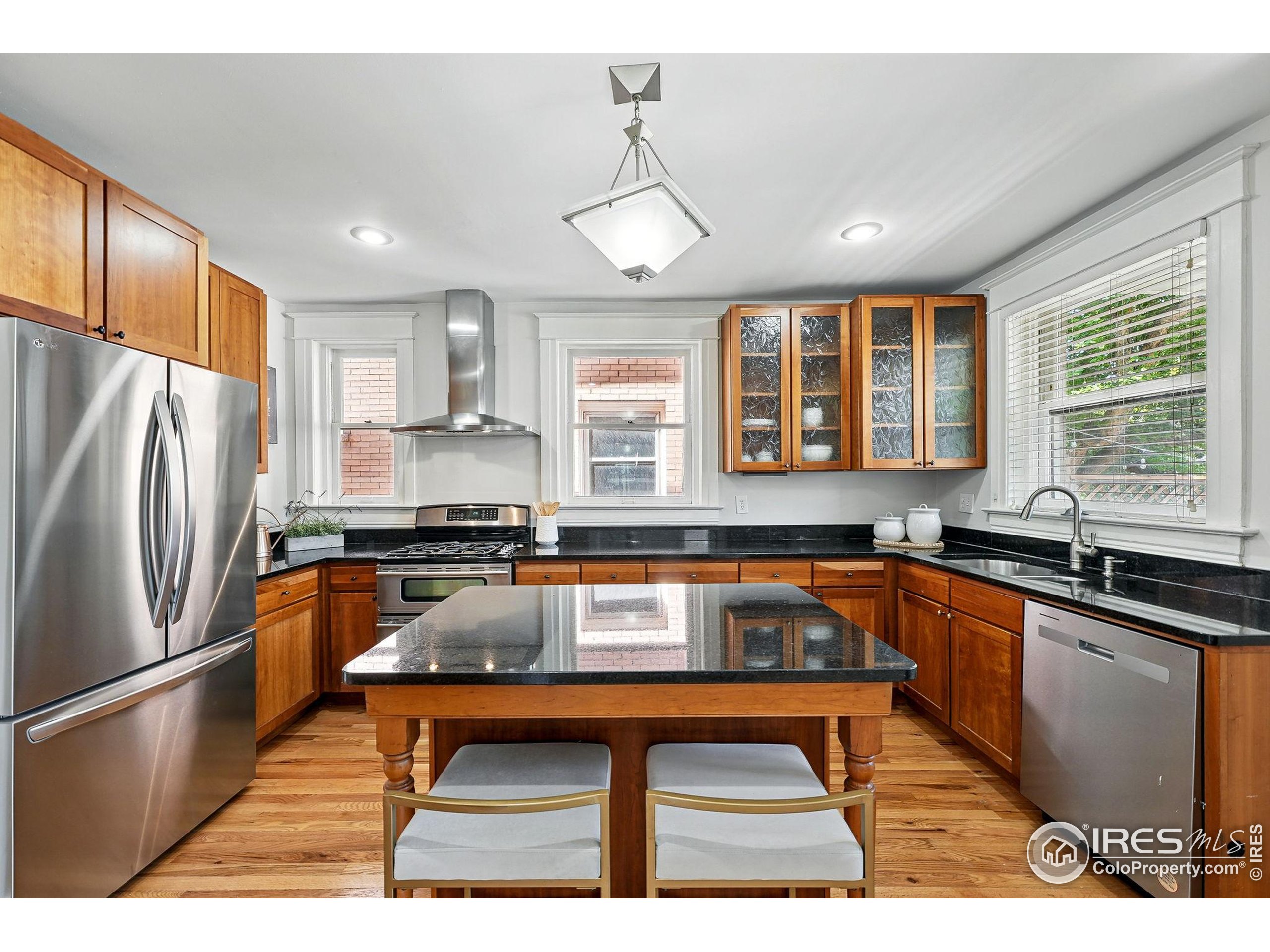 1582 Steele Street Denver, CO 80206 - Photo 18 of 48 a kitchen with stainless steel appliances granite countertop a refrigerator a sink dishwasher a stove and white countertops with wooden floor