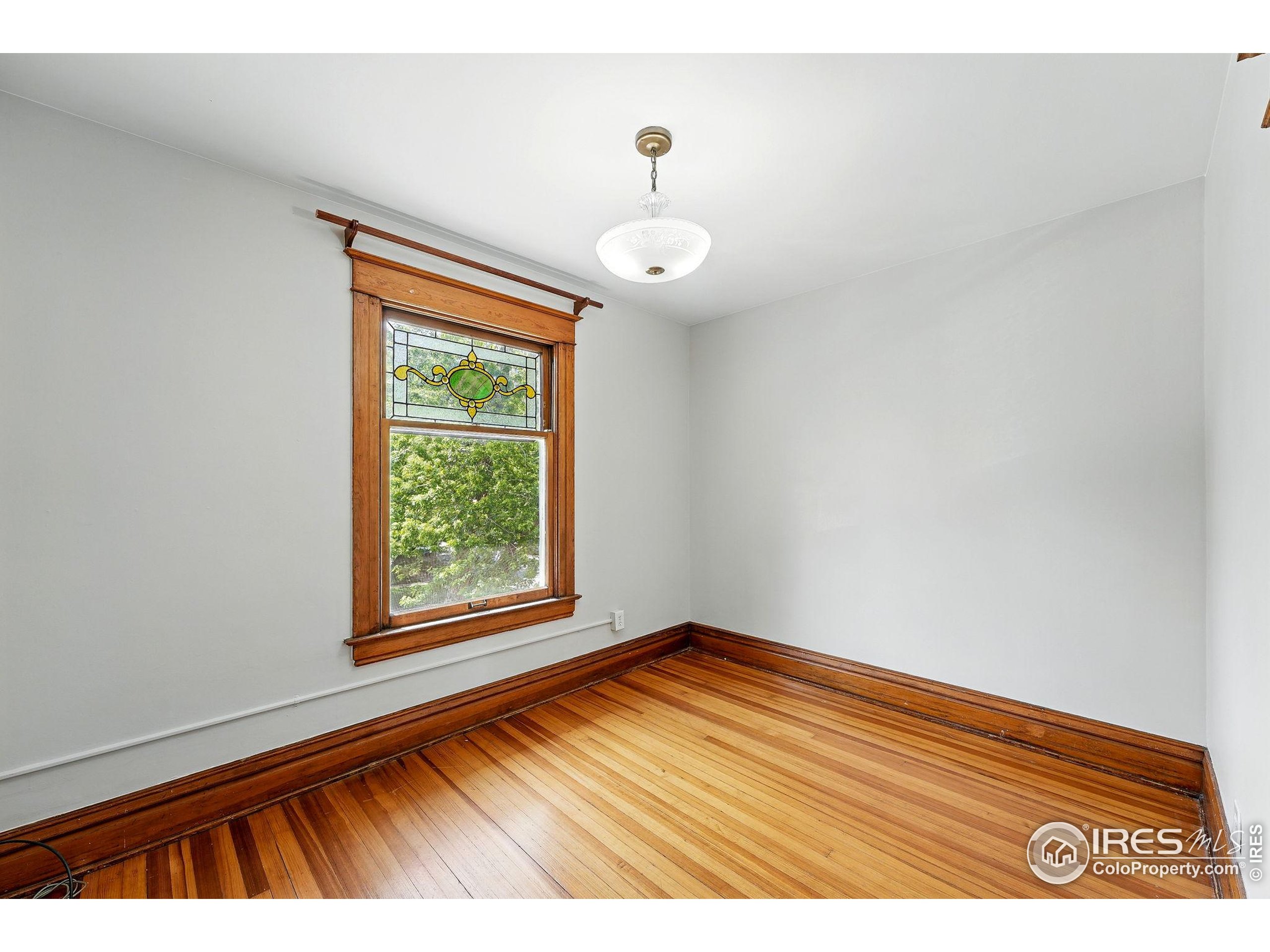 1582 Steele Street Denver, CO 80206 - Photo 32 of 48 a view of an empty room with wooden floor and a window