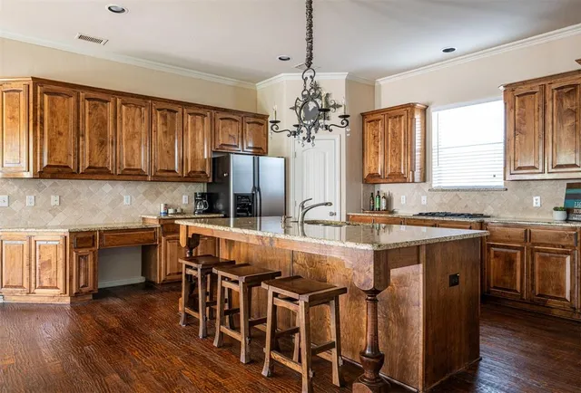 a kitchen with stainless steel appliances granite countertop a stove top oven a sink dishwasher a dining table and chairs with wooden floor