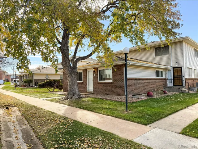 a view of a white house next to a yard and road