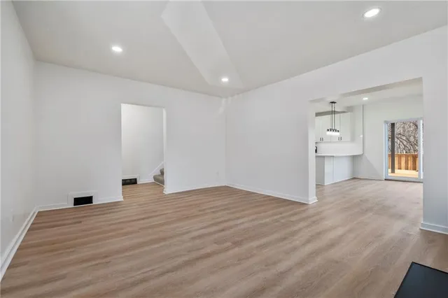 a view of empty room with wooden floor and windows
