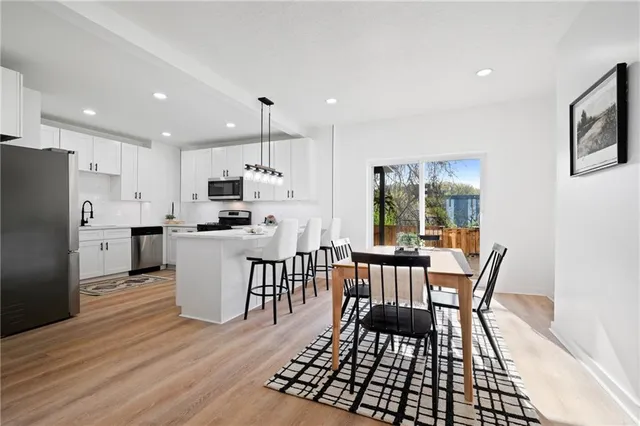 a kitchen with stainless steel appliances granite countertop a stove a kitchen island a dining table and chairs