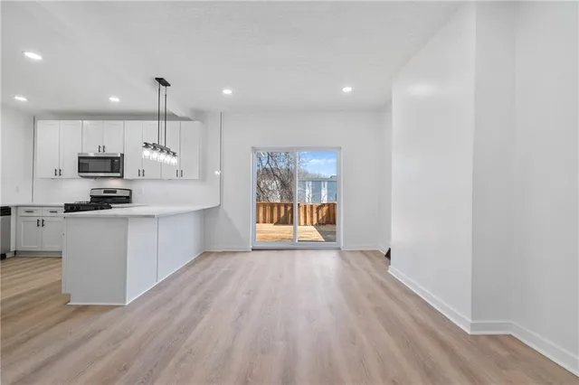 a large kitchen with stainless steel appliances granite countertop a stove a sink and white cabinets with wooden floor