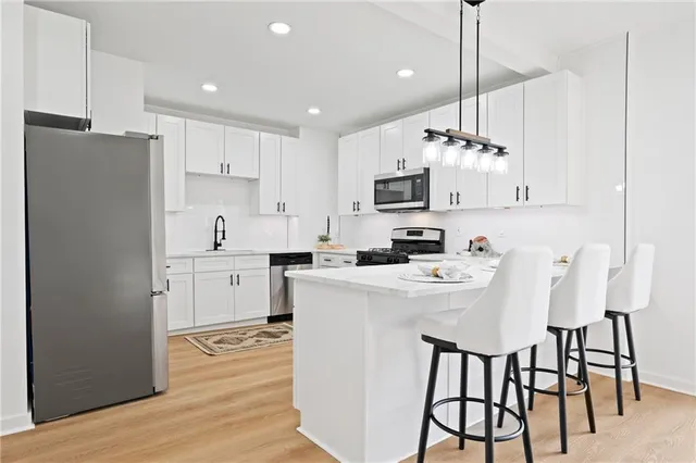 a kitchen with kitchen island white cabinets and stainless steel appliances