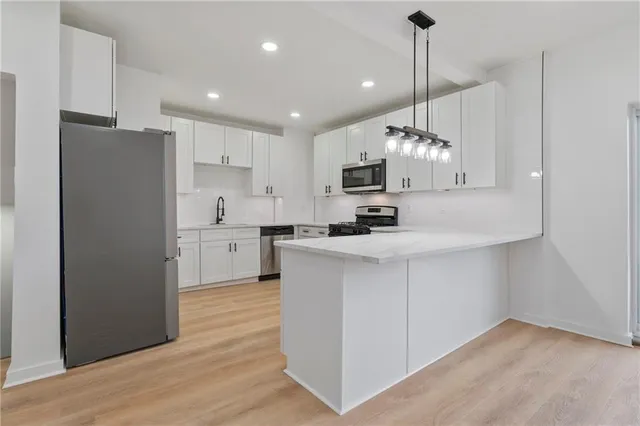 a kitchen with kitchen island a white counter top space cabinets and stainless steel appliances