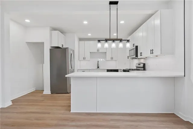 a kitchen with stainless steel appliances granite countertop a refrigerator a sink dishwasher a oven and white cabinets with wooden floor