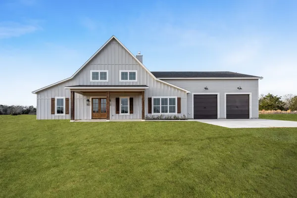 a front view of a house with a garden and trees