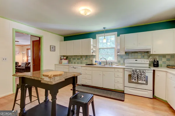 a kitchen with stainless steel appliances granite countertop a stove a refrigerator a dining table and chairs with wooden floor