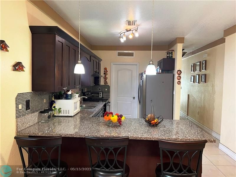 a kitchen with granite countertop kitchen island stainless steel appliances a sink stove and refrigerator