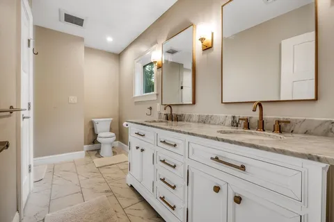 a bathroom with a granite countertop sink mirror and toilet