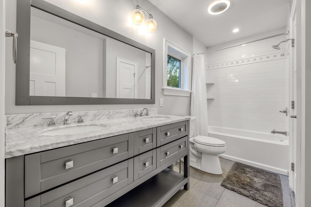 540 Pulaski Boulevard Bellingham, MA 02019 - Photo 32 of 42 a bathroom with a granite countertop toilet a sink and a bathtub