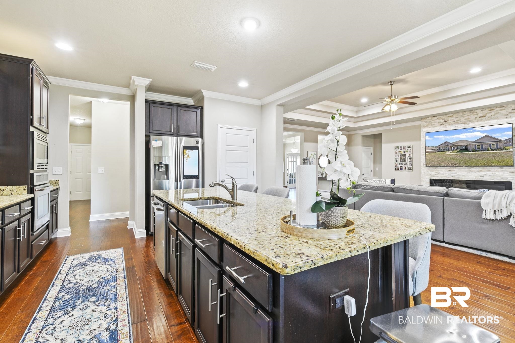 31500 Spoonbill Road Daphne, AL 36527 - Photo 18 of 85 Kitchen with sink, ornamental molding, light stone countertops, dark hardwood / wood-style floors, and a kitchen island with sink