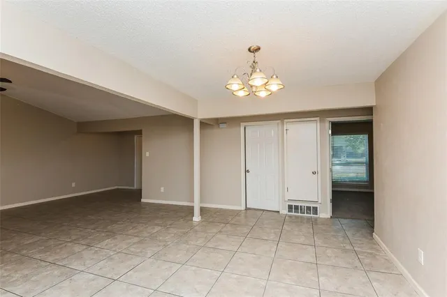 an empty room with a fireplace and chandelier fan