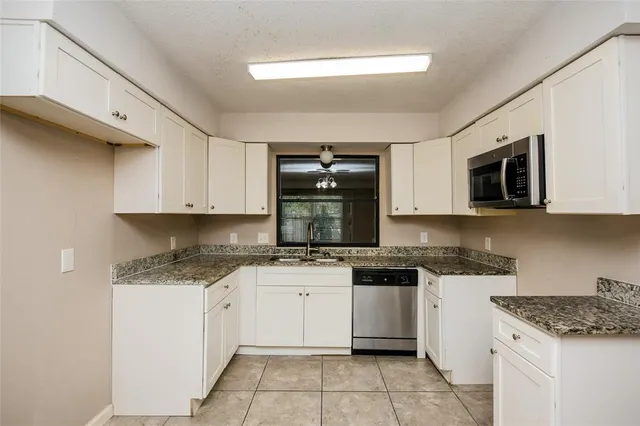 a kitchen with granite countertop white cabinets sink and stainless steel appliances