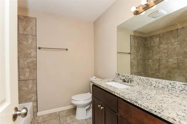 a bathroom with a granite countertop sink a toilet and shower