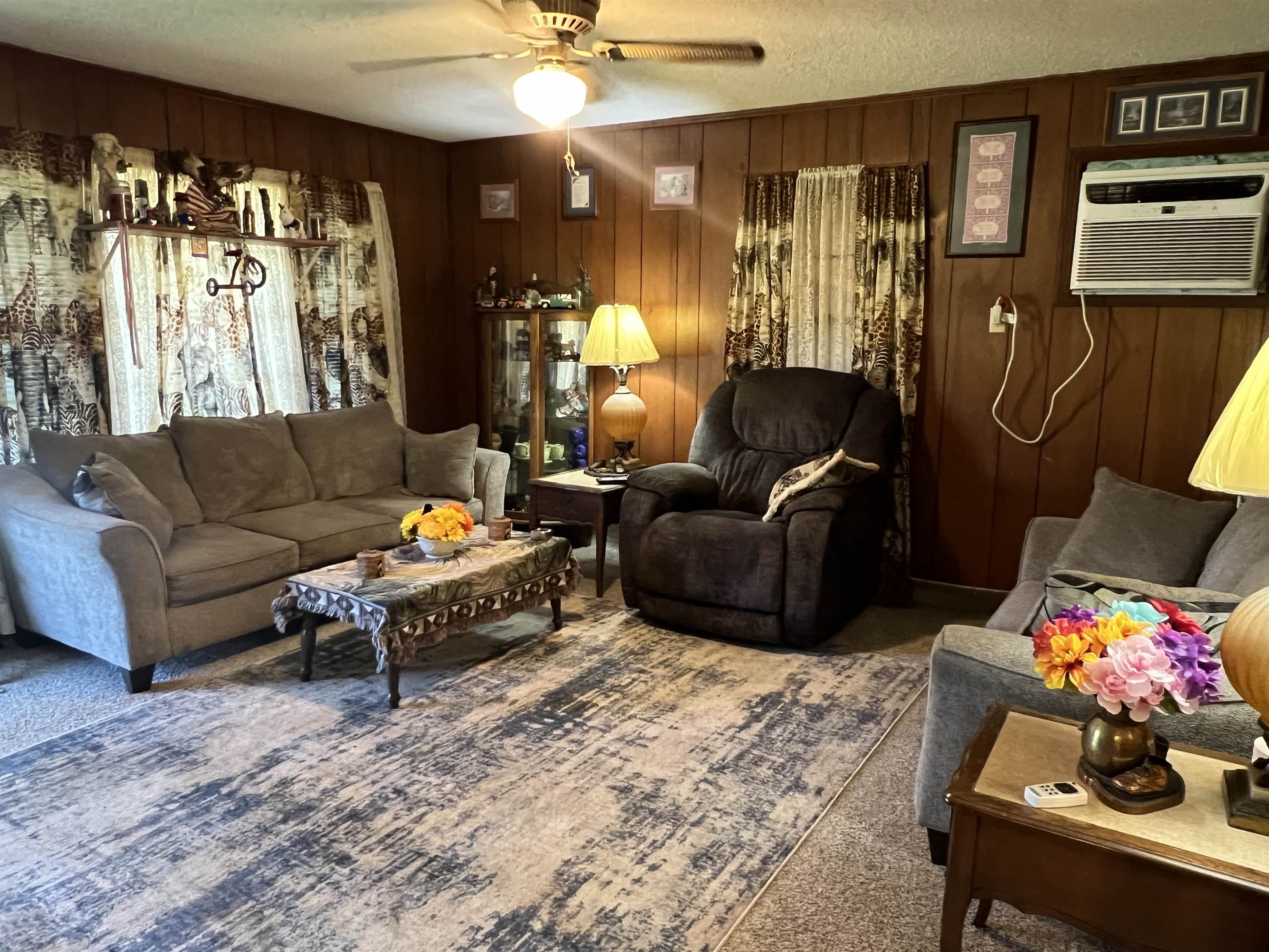 135 Angotti Road Crump, TN 38327 - Photo 7 of 29 Carpeted living room featuring an AC wall unit, a textured ceiling, ceiling fan, and wooden walls