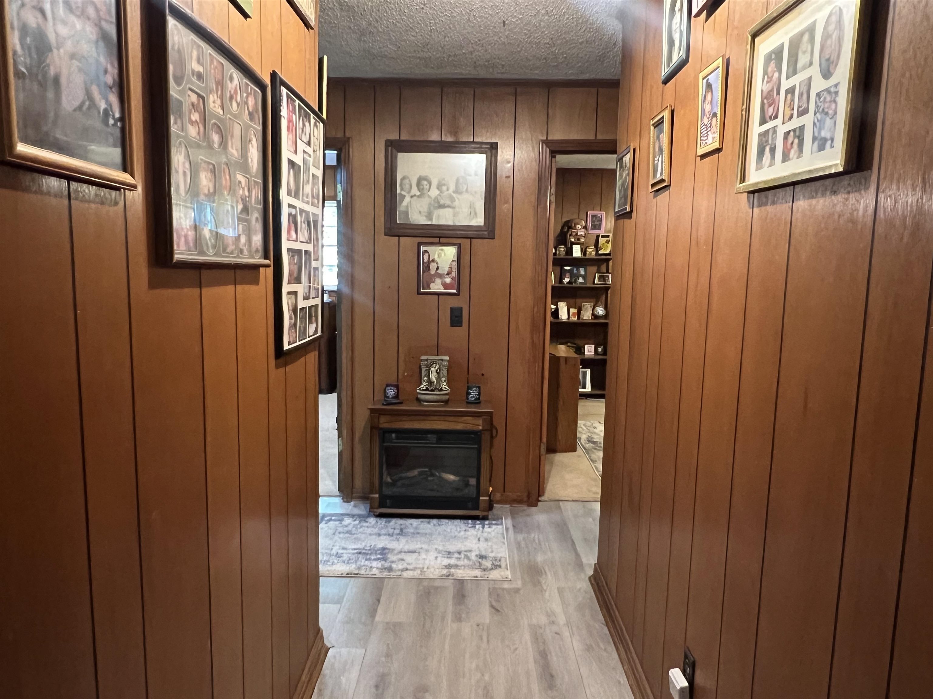 135 Angotti Road Crump, TN 38327 - Photo 10 of 29 Hall with a textured ceiling, hardwood / wood-style flooring, and wooden walls