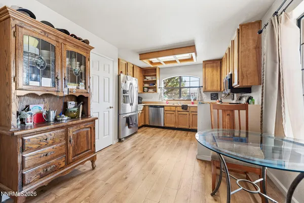 a kitchen with stainless steel appliances a stove top oven a sink a dining table and chairs