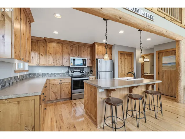 a kitchen with stainless steel appliances kitchen island a table chairs in it and wooden floors