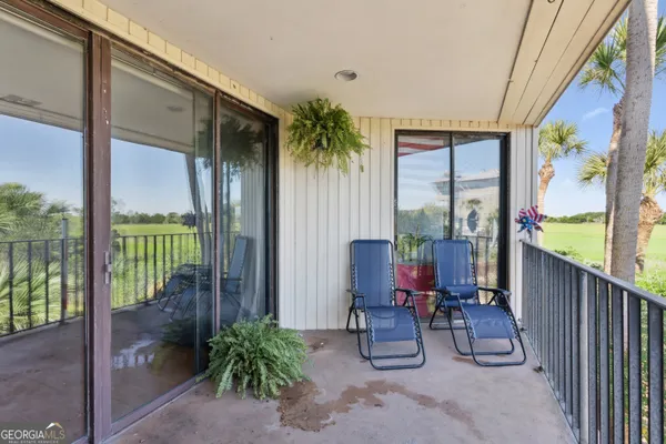 a view of a porch with chairs and floor to ceiling window