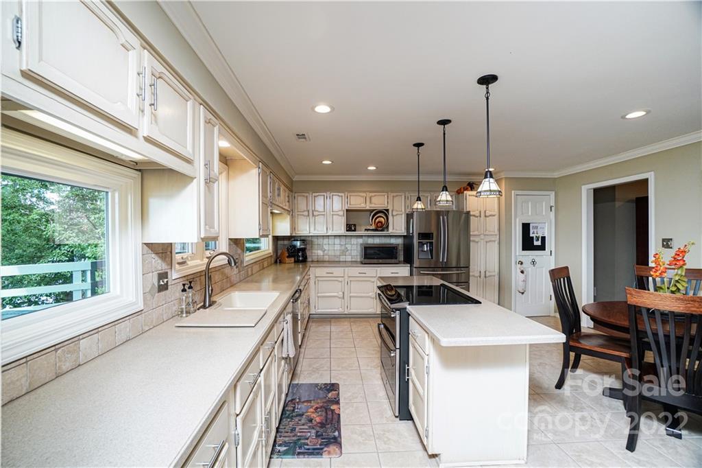 8032 Windjammer Drive Tega Cay, SC 29708 - Photo 10 of 48 a view of a kitchen with kitchen island stainless steel appliances sink stove dining table and chairs