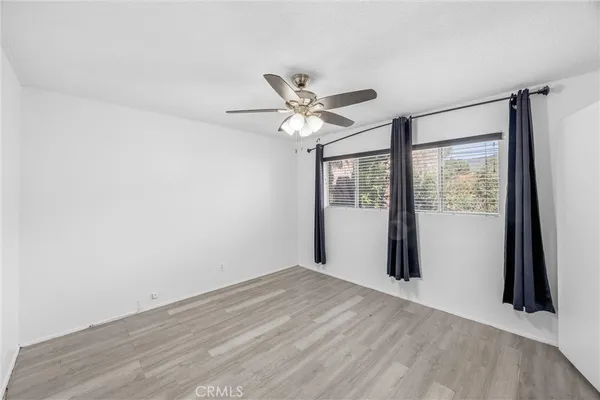 a view of empty room with wooden floor and ceiling fan