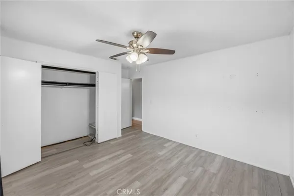 a view of empty room with wooden floor and ceiling fan