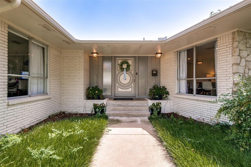 White brick exterior with stone accents, covered entry, and large windows