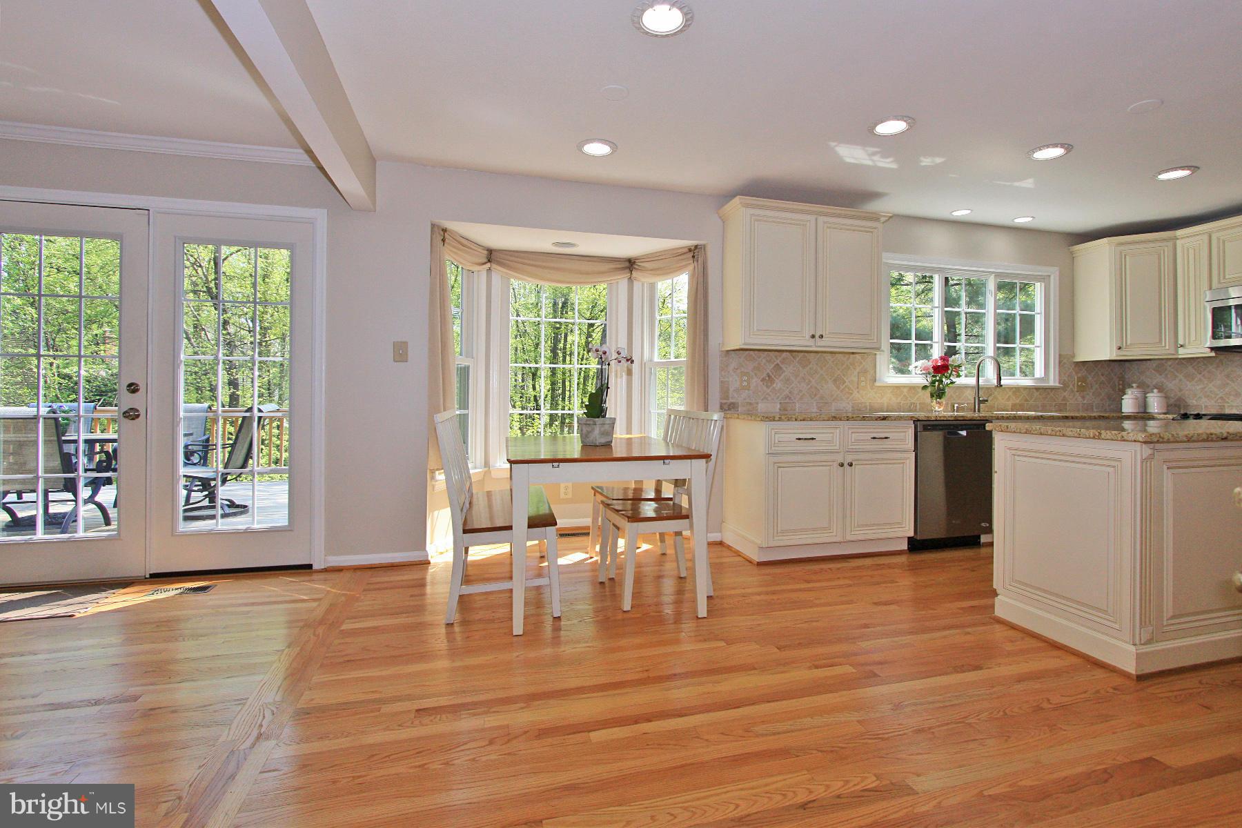 1613 Stowe Road Reston, VA 20194 - Photo 8 of 30 a kitchen with stainless steel appliances granite countertop a stove top oven a sink dishwasher a dining table and chairs with wooden floor