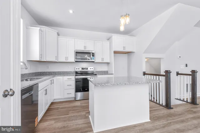 a kitchen with stainless steel appliances granite countertop a stove a sink dishwasher and a refrigerator with wooden floor