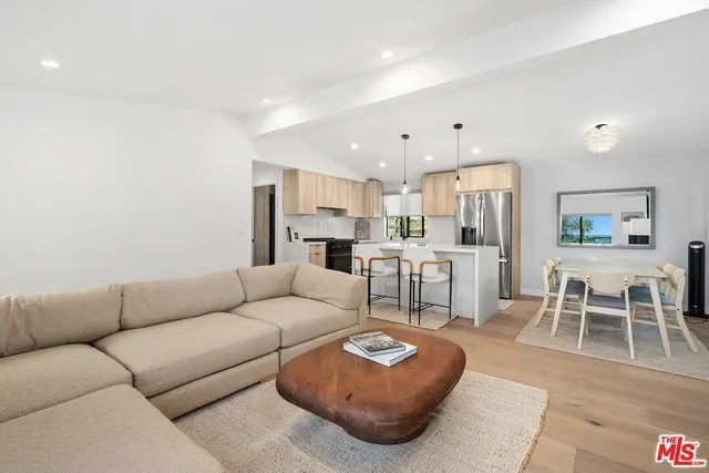 a kitchen with kitchen island a stove a refrigerator a sink and a dining table with wooden floor