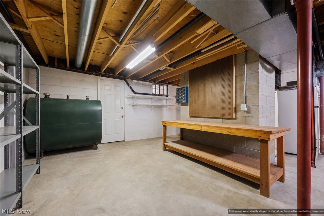 1835 Lynn Road Kent, OH 44240 - Photo 42 of 48 Utility space featuring a wood workbench, pegboard, concrete block walls, exposed wood ceiling joists, and a concrete floor