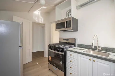 a kitchen with stainless steel appliances granite countertop white cabinets a stove top oven a sink and dishwasher