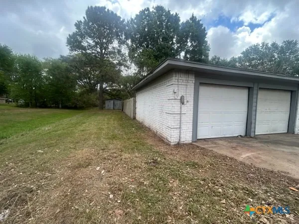 a backyard of a house with large trees and a small barn