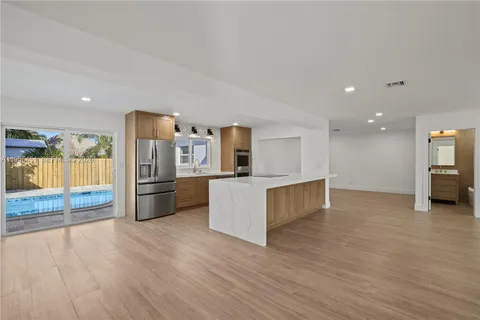 a large kitchen with stainless steel appliances a large counter top a stove and a refrigerator