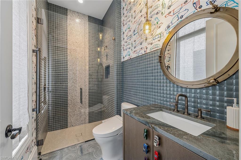 2243 Residence Circle Naples, FL 34105 - Photo 21 of 29 a bathroom with a sink a mirror a toilet and a shower