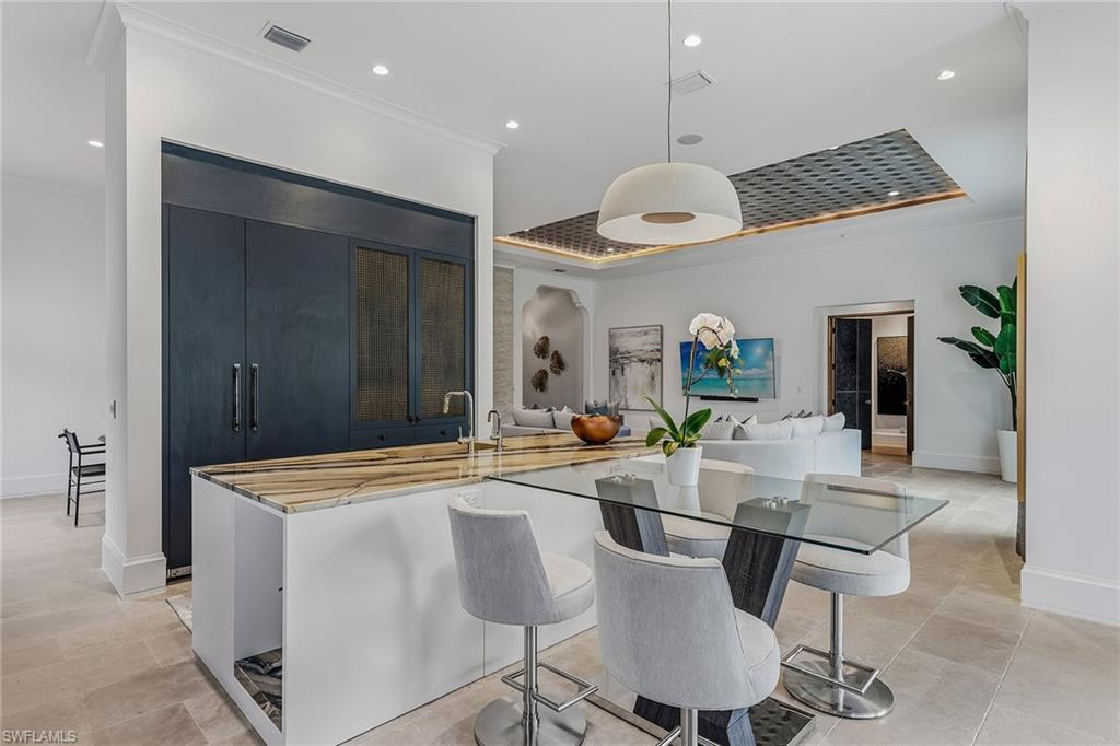 2243 Residence Circle Naples, FL 34105 - Photo 5 of 29 a dining room with wooden floor a chandelier a wooden table and chairs