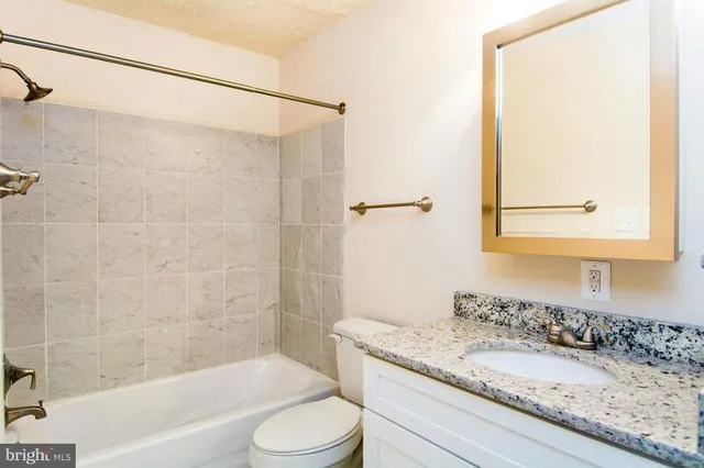 a bathroom with a granite countertop sink toilet and shower
