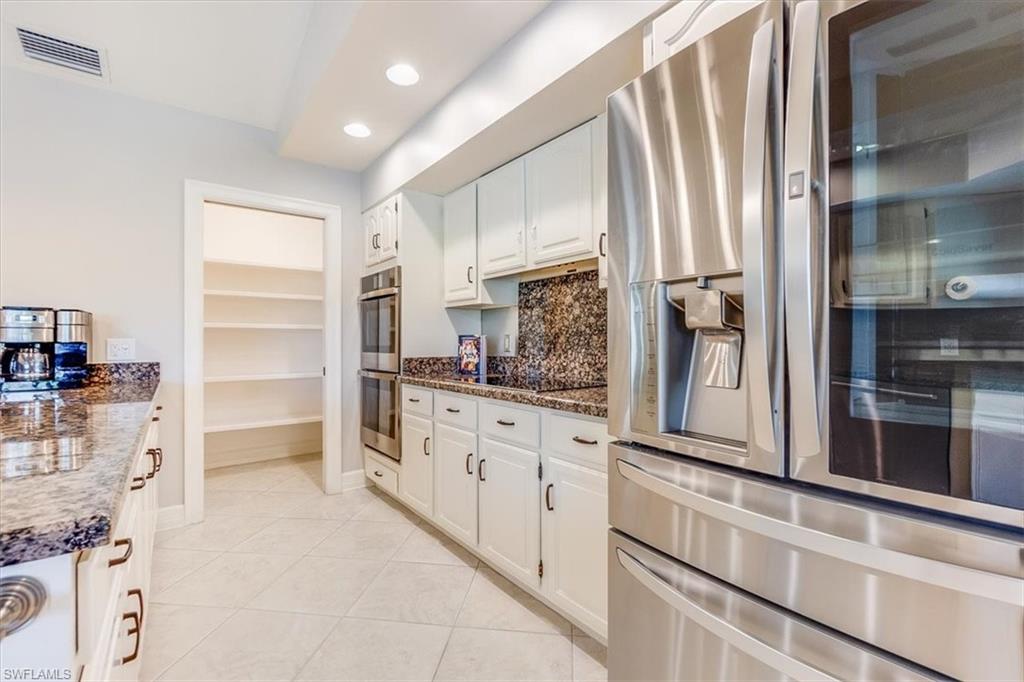 2209 Regal Way Naples, FL 34110 - Photo 7 of 49 a kitchen with granite countertop white cabinets and stainless steel appliances