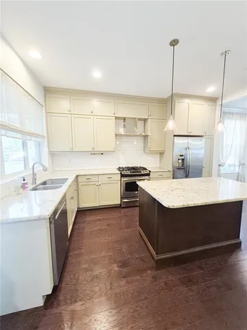 a kitchen with stainless steel appliances granite countertop a sink a stove and a refrigerator