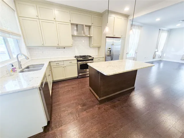a kitchen with stainless steel appliances kitchen island a sink stove and cabinets