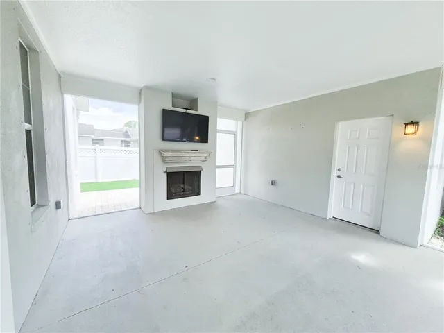 a view of an empty room with a window and kitchen view