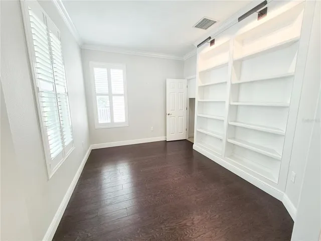a view of an empty room with a window and wooden floor