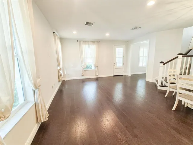 a view of an empty room with wooden floor and chair