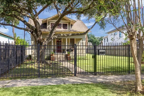 a view of a white house with a large tree and plants