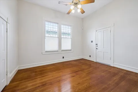 a view of an empty room with wooden floor and a window