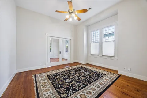 a view of a bedroom with wooden floor and a ceiling fan