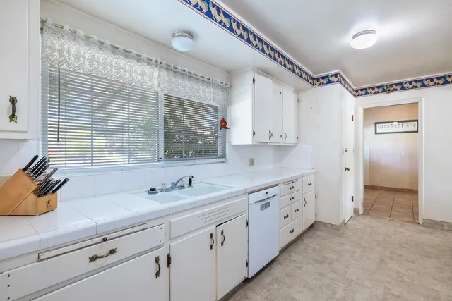 a large white kitchen with stainless steel appliances granite countertop lots of counter space and a sink